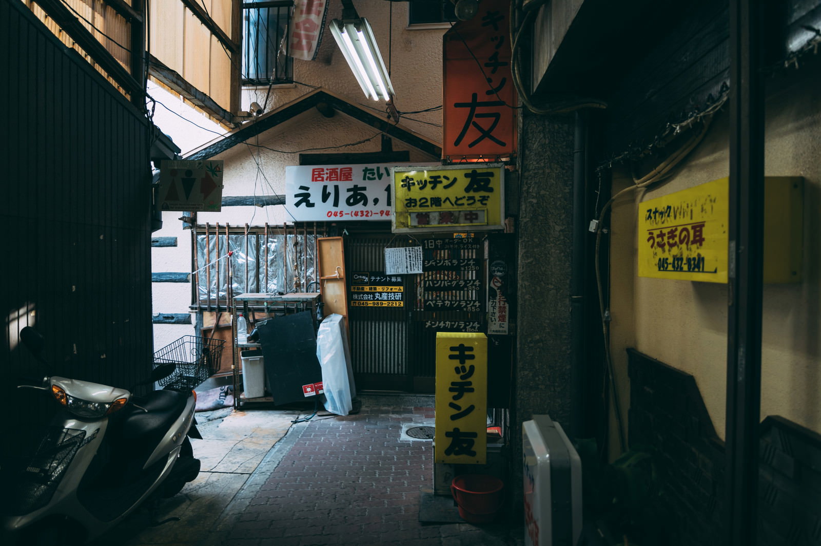 薄暗い照明の六角橋仲見世通り、左右に小さな店舗が並ぶ商店街