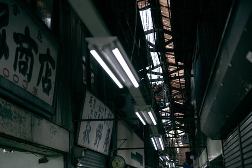 商店街の天井からぶら下がる蛍光灯の照明風景