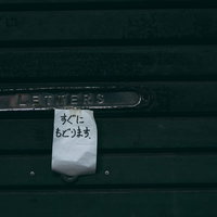 シャッターに貼られたメモ「すぐにもどります」の写真