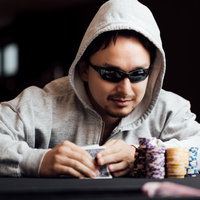 サングラスをかけたギャンブラー男性がカジノのチップを前に考えるの写真