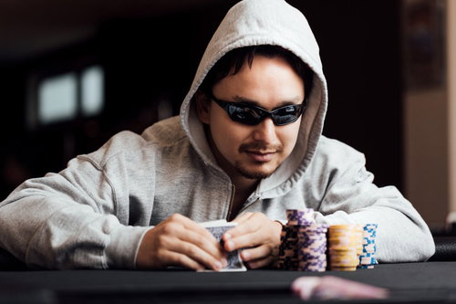 サングラスをかけたギャンブラー男性がカジノのチップを前に考える