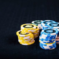 黒いテーブルに積まれたカラフルなカジノのチップの写真