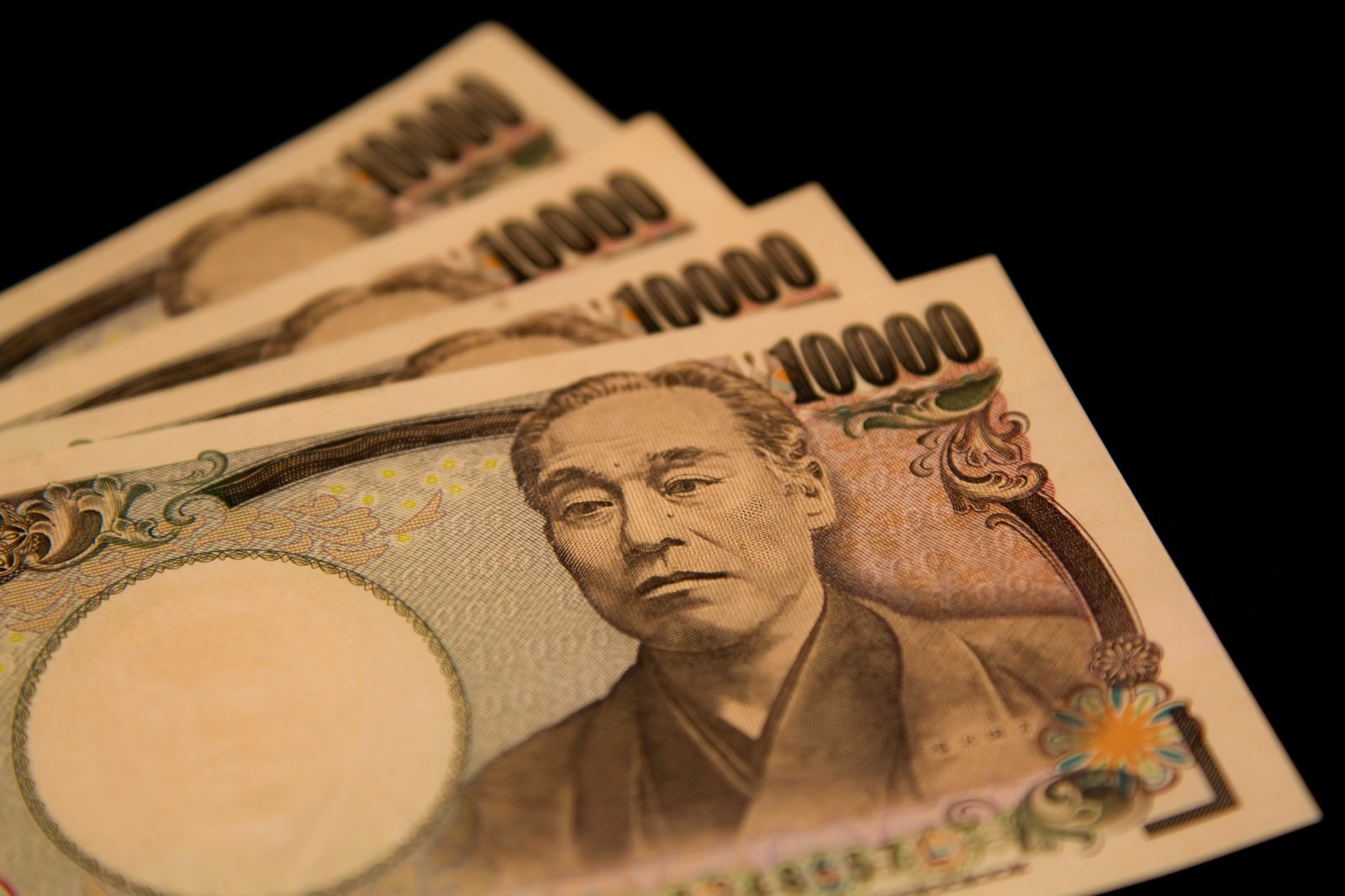 黒い背景に並んだ4枚の壱万円札