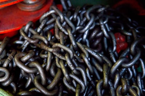 赤い容器に積まれた錆びたチェーンブロックの鎖