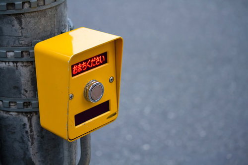 「おまちください」と書かれた歩行者用押しボタン式信号の接写