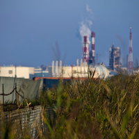 フェンス越しに見える遠くの工業地帯の写真