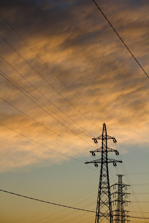 夕焼け空にそびえる鉄塔と電線