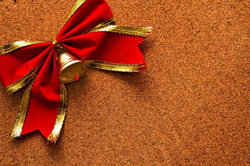 コルクボードに置かれた赤いリボンと金のベル