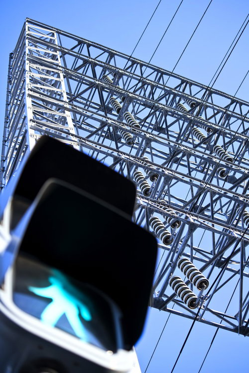 青空を背景にした歩行者信号と送電鉄塔