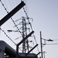 鉄塔を背景にした工業地帯の有刺鉄線の写真