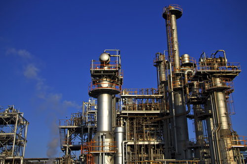 青空にそびえる工業地帯の配管と塔