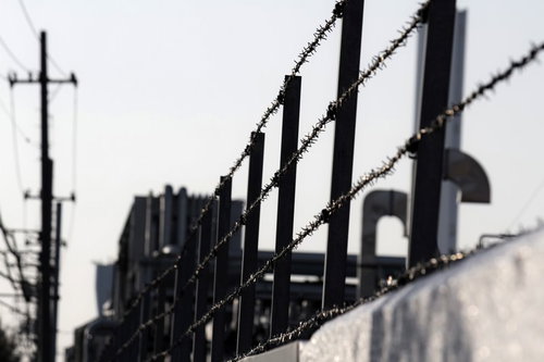 曇り空を背景に張られた工場の有刺鉄線