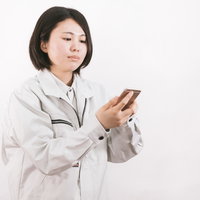 日報をスマートフォンで入力する現場作業員の写真