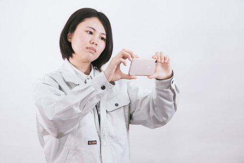 原状回復確認用にスマホで撮影する作業着姿の現場責任者