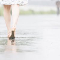 雨上がりの道を歩く足元、水たまりに映る反射の写真