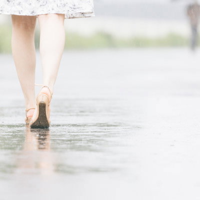 雨上がりの道を歩く足元、水たまりに映る反射の写真