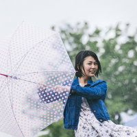 雨に唄えば、水玉傘を持つ女性が雨の中で楽しそうに踊るの写真