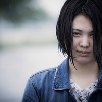 雨にびしょ濡れになった女性の薄ら笑い、濡れ髪とデニムジャケットの写真