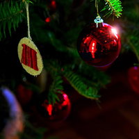 暗い室内で光るクリスマスツリーの赤いガラス玉飾りの写真