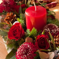 赤いろうそくと薔薇が添えられたクリスマスの花飾りの写真