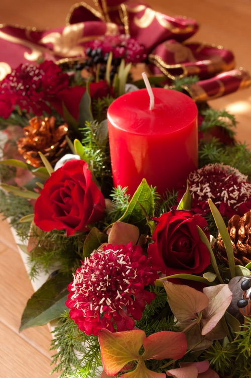 赤いろうそくと薔薇が添えられたクリスマスの花飾り