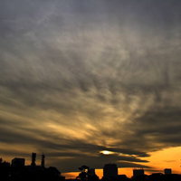 雲の間から差す光が広がる皇居からの夕暮れの写真