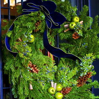 黒い門に飾られた青いリボンのクリスマスリースの写真