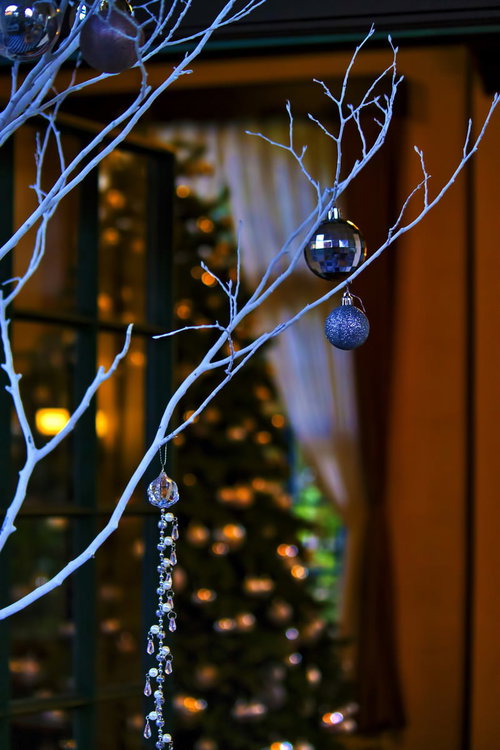 銀色と青の飾りが吊るされた白い枝のツリー