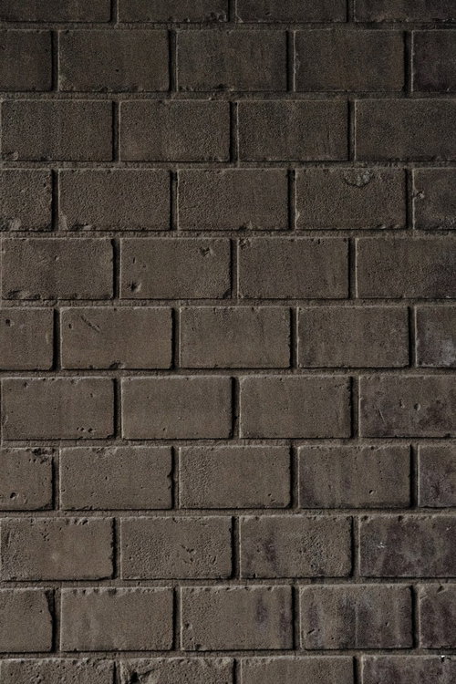 細かい穴や傷が残る薄汚れたレンガ塀