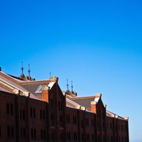 快晴の青空の下に建つ赤レンガの集合住宅の写真