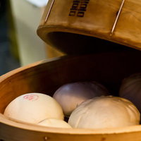 木の蒸し器に並ぶ白い中華まんとせいろの写真