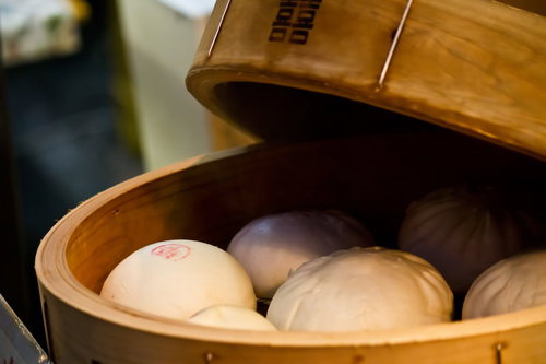 木の蒸し器に並ぶ白い中華まんとせいろ