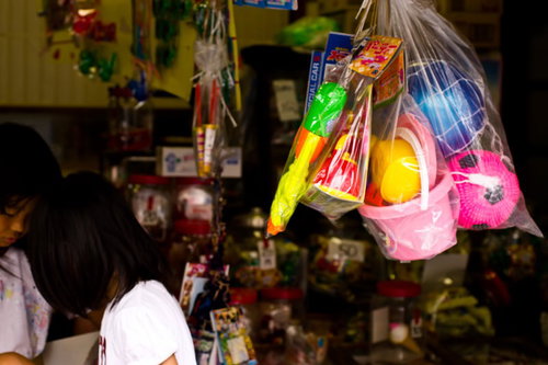 カラフルなおもちゃが吊り下がる駄菓子屋の店先