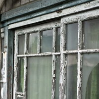 ペンキが剥がれた木枠の古くボロボロな窓の写真