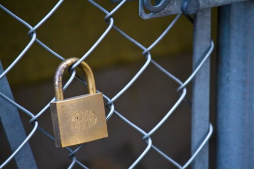 金網フェンスに掛かる真鍮色の南京錠