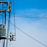 変圧器と電線が付いた真夏日の電柱と入道雲の青空の写真