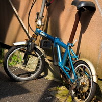 壁に立てかけたパンクした錆びた青い自転車の写真