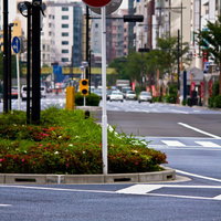 都市の道路に立つ赤い進入禁止の標識と街並みの写真