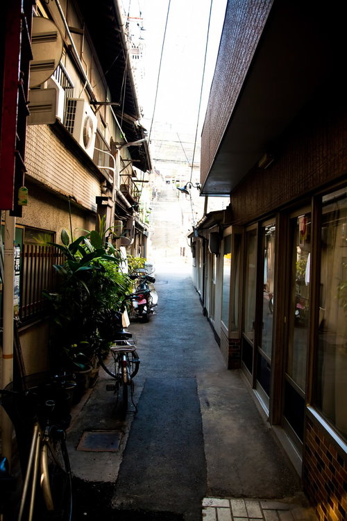自転車やバイクが停まる下町の路地裏の風景
