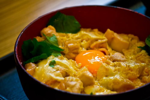 赤い椀に盛った生卵のせの親子丼