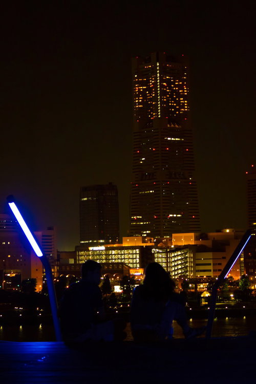 窓明かりが並ぶ夜のランドマークタワーと恋人のシルエット