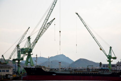港に停泊する大型船と緑のクレーンがある尾道の造船所