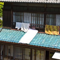 瓦屋根に白い布団を干す日本の伝統的な民家の写真