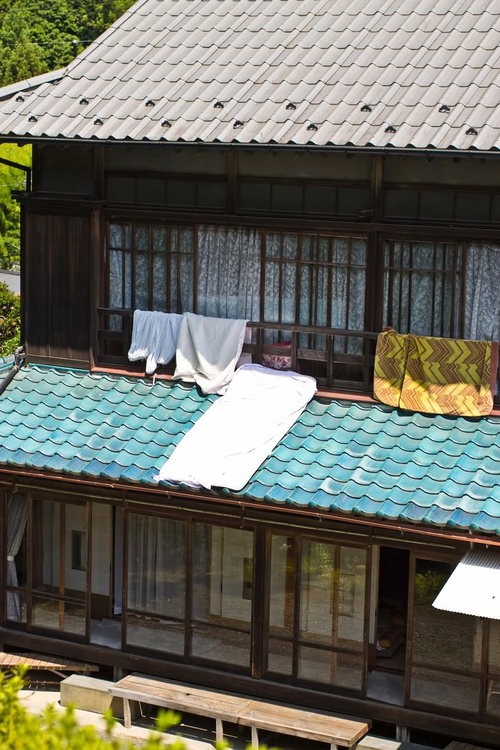 瓦屋根に白い布団を干す日本の伝統的な民家