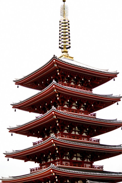 雪が積もる五重の塔の赤い屋根と金色の頂上