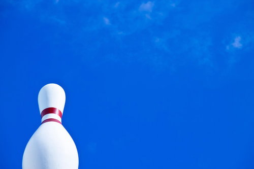 青い背景に立つ赤い帯のボーリング場の巨大ピン