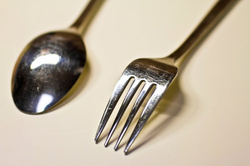 明るい台の上に横に並べた銀のスプーンとフォーク