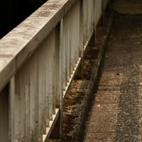 雨に濡れたコンクリートの上の古びた陸橋の白い手すりの写真
