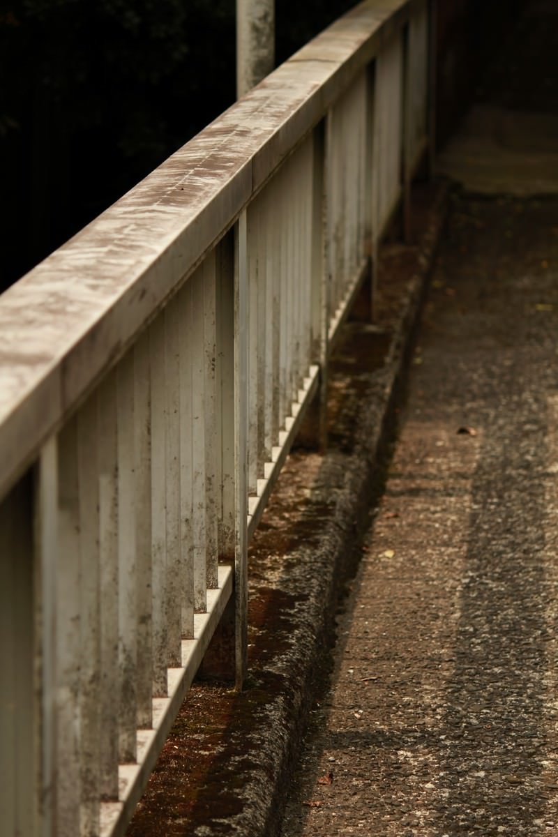 雨に濡れたコンクリートの上の古びた陸橋の白い手すり