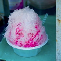 ピンクのシロップがかかった山盛りのイチゴのカキ氷の写真